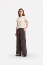 Brown wide-leg Tencel fabric pants with pleats and loose fit, stylishly displayed on a hanger.