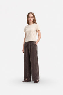 Brown wide-leg Tencel fabric pants with pleats and loose fit, stylishly displayed on a hanger.